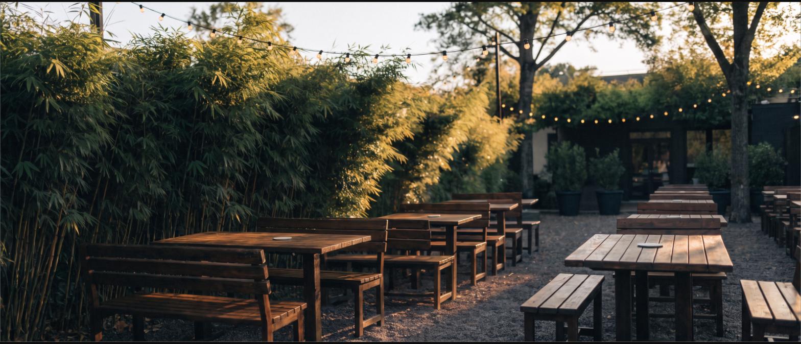 Outdoor restaurant patio screened along one side by a tall bamboo hedge